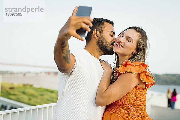 Mann küsst und macht Selfie mit schwangerer Frau