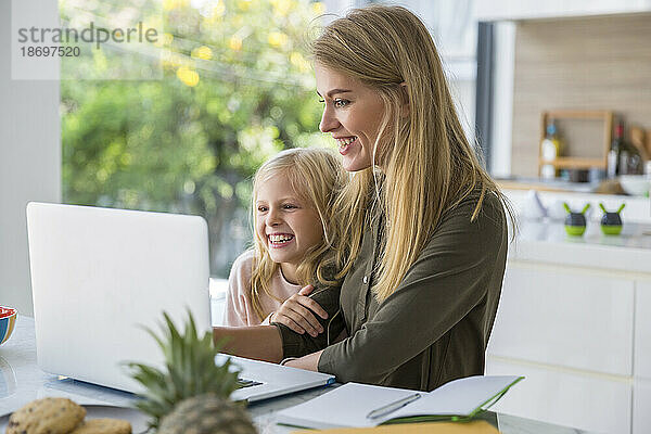 Glückliche Frau  die zu Hause den Laptop ihrer Tochter benutzt