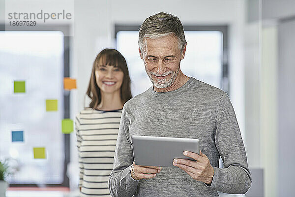 Geschäftsmann nutzt Tablet-PC mit Kollegen im Hintergrund