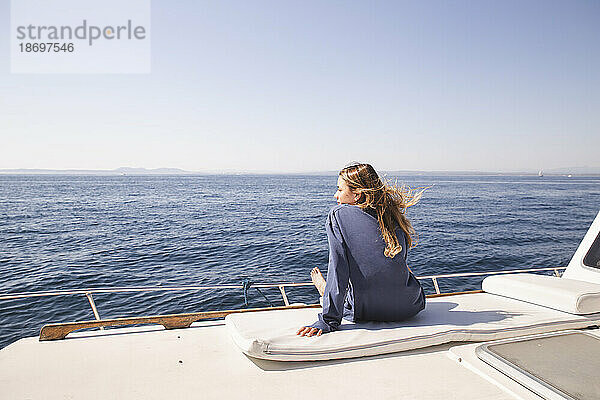 Frau sitzt an sonnigem Tag auf Bootsdeck