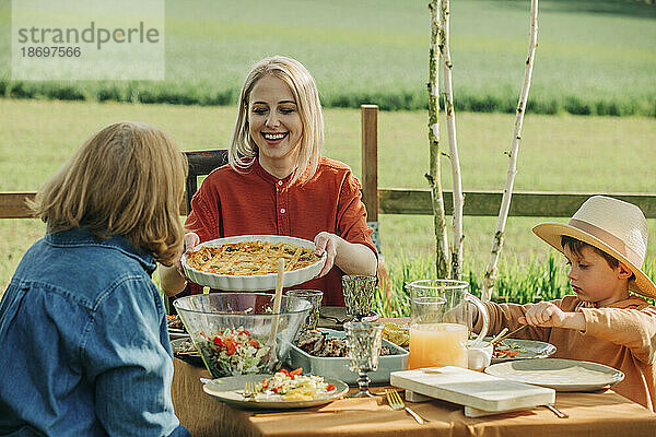 Glückliche Familie beim gesunden Mittagessen am Esstisch im Hinterhof