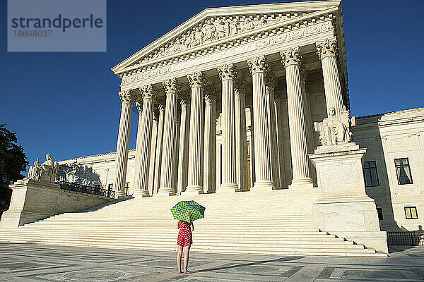 Frau mit Regenschirm in leuchtenden Farben blickt auf den Obersten Gerichtshof der USA in Washington  DC  USA; Washington  District of Columbia  Vereinigte Staaten von Amerika