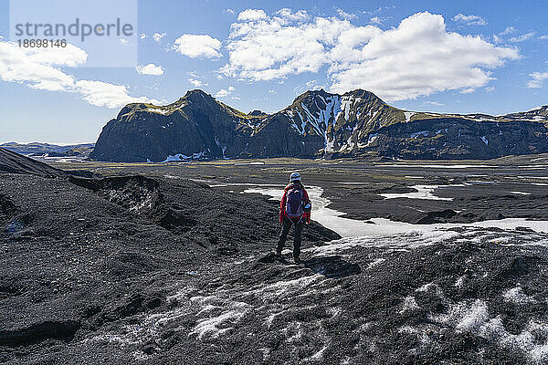 Frau steht auf einem Gletscher und blickt auf die Berglandschaft an der Südküste Islands; Vik  Südisland  Island