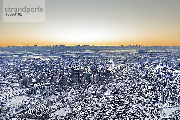 Stadt Calgary in einer Schneedecke bei Sonnenuntergang  mit den Silhouetten der Rocky Mountains in der Ferne  in Alberta  Kanada; Calgary  Alberta  Kanada