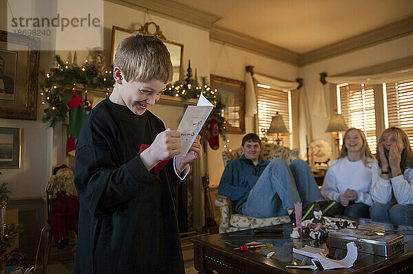 Kleiner Junge erhält in seinem Haus eine Geburtstagskarte und ein Geschenk  während seine Familie zusieht; Lincoln  Nebraska  Vereinigte Staaten von Amerika