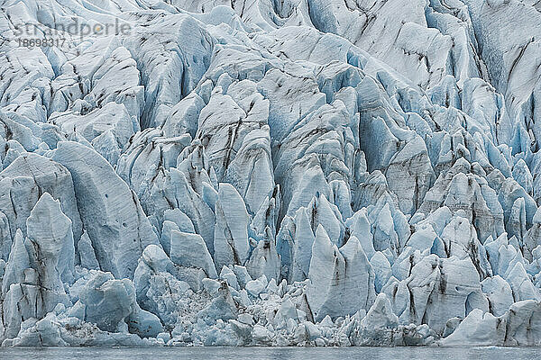 Atemberaubender Blick auf die schlammdurchzogenen  gezackten blauen Eisformen eines Gletscherendpunkts; Südisland  Island