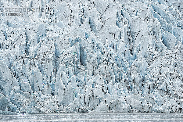 Atemberaubender Blick auf die schlammdurchzogenen  gezackten blauen Eisformen eines Gletscherendpunkts; Südisland  Island