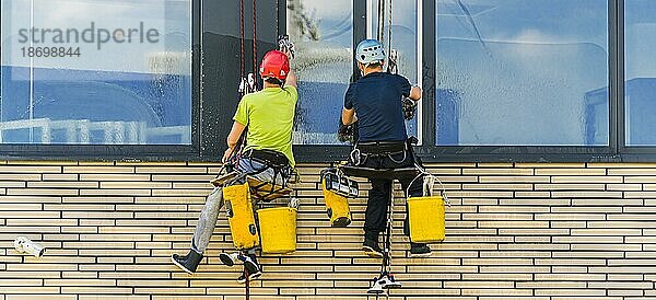 Zwei Männer putzen Fenster eines Bürogebäudes