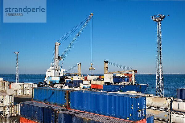 Hafenkran beim Beladen eines kommerziellen Containerschiffs mit Frachtcontainern und Autos in einem Industriehafen. Lissabon  Portugal  Europa