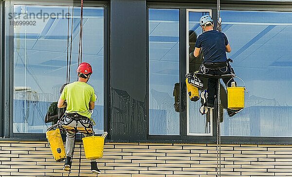 Zwei Männer putzen Fenster eines Bürogebäudes