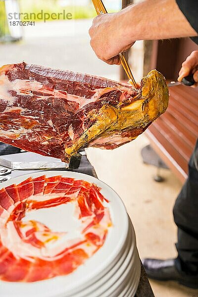 Iberischer Schinkenmesser Mann. Service von einer Person  die ein Stück Schinken schneidet. Koch oder Cutter mit einem Messer schneiden Scheiben. traditionelle Lebensmittel von Spanien