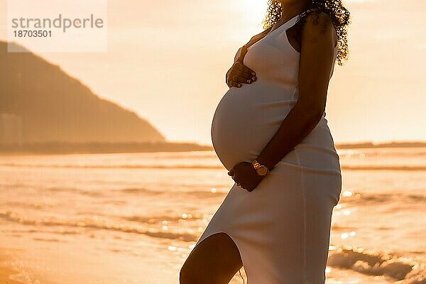 Schwangere Mutterschaft latin Frau am Strand bei Sonnenuntergang  Mutterschaft Konzept. Frau Silhouette