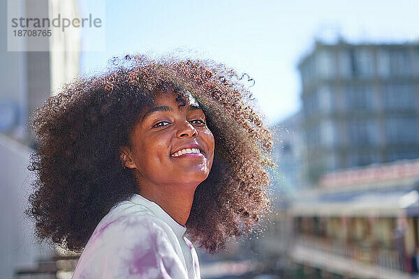 Porträt einer glücklichen  selbstbewussten jungen Frau in einer sonnigen Stadt