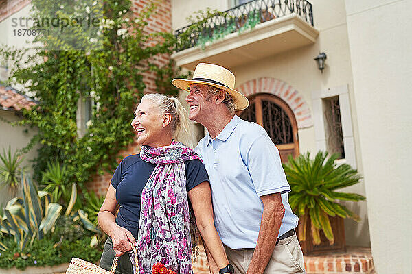 Glückliches älteres Paar schaut vor der sonnigen Villa weg