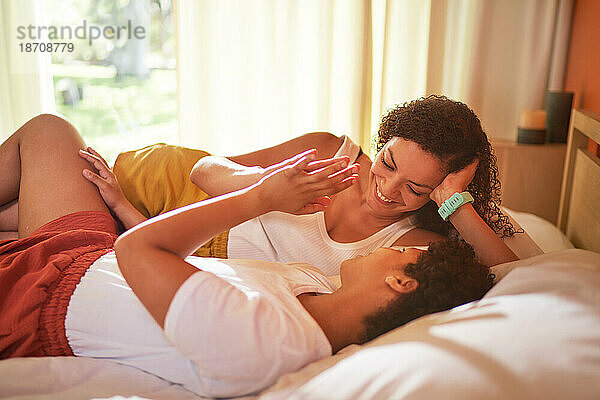 Liebevolles lesbisches Paar hält Händchen auf dem Bett im Morgenschlafzimmer