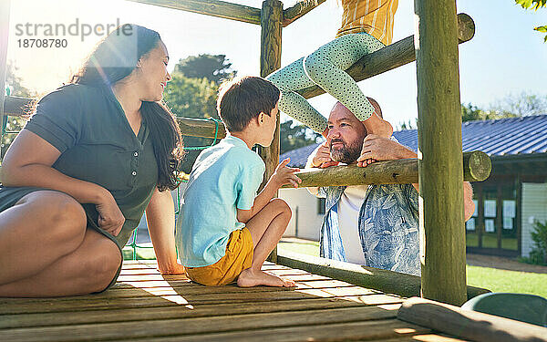 Glückliche Familie spielt auf dem Spielplatz im sonnigen Park