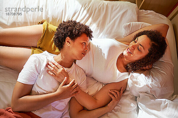 Liebevolles lesbisches Paar  das morgens im Bett kuschelt und redet