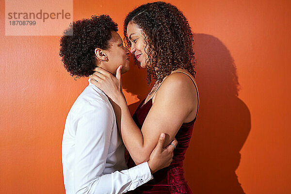 Porträt eines glücklichen lesbischen Paares mit lockigem Haar  das von Angesicht zu Angesicht lächelt