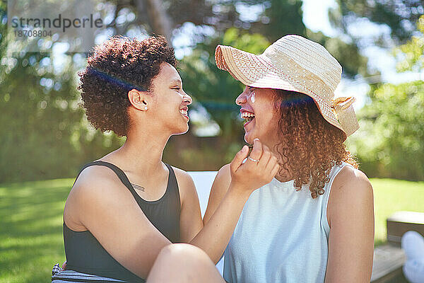 Glückliches  liebevolles lesbisches Paar  das im sonnigen Sommerhinterhof lacht