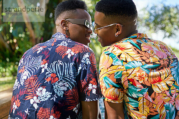 Liebevolles schwules Männerpaar in Hawaiihemden küsst sich