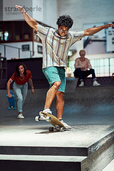 Junger Mann fährt Skateboard auf Sportrampe im Skateboardpark