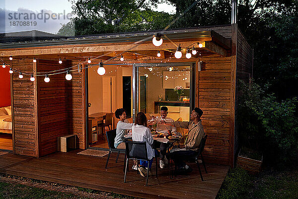 Fröhliches Freundespaar genießt das Abendessen am sommerlichen Terrassentisch