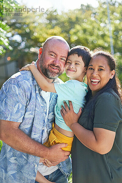 Porträt glücklicher Eltern  die ihren Sohn mit Down-Syndrom halten