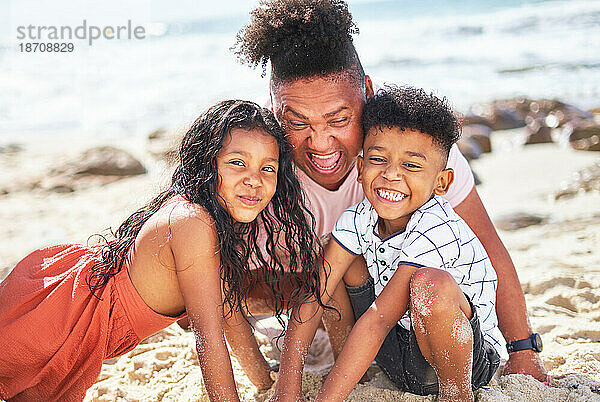 Porträt einer glücklichen  verspielten Familie  die am sonnigen Sommerstrand im Sand wühlt