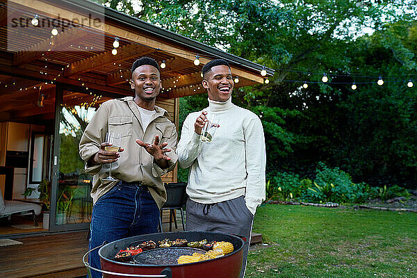 Porträt eines glücklichen jungen schwulen männlichen Paares beim Trinken und Grillen