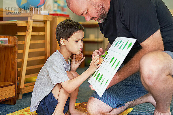 Vater und Sohn mit Down-Syndrom lernen zu Hause etwas über Pflanzen