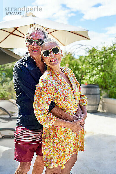 Porträt eines glücklichen älteren Paares  das sich auf der sonnigen Sommerterrasse umarmt