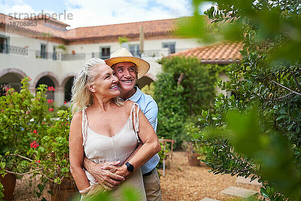 Glückliches älteres Paar umarmt sich im Garten vor der Sommervilla