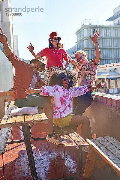 Porträt glücklicher junger Freunde  die auf dem sonnigen Stadtdach jubeln