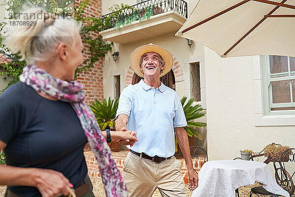 Fröhliches  unbeschwertes Seniorenpaar tanzt vor der Sommervilla