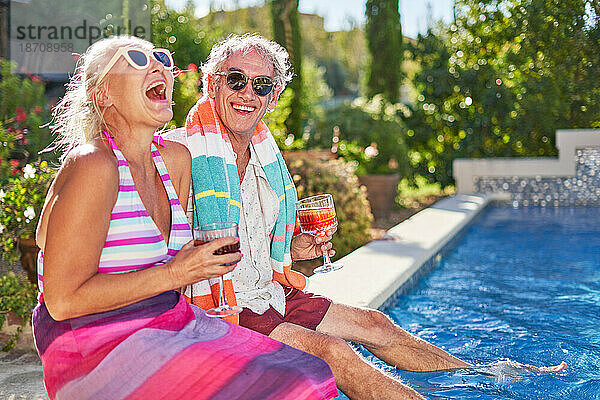 Porträt eines glücklichen  unbeschwerten Seniorenpaares  das im Sommerschwimmbad lacht