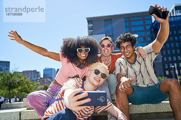 Fröhliche  unbeschwerte junge Freunde machen Selfie im sonnigen Stadtpark