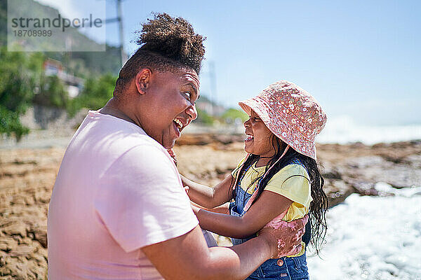 Glücklicher Vater und Tochter lachen am sonnigen Sommerstrand