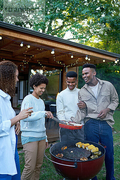 Glückliches schwules männliches Paar grillt mit lesbischen Freunden im Hinterhof