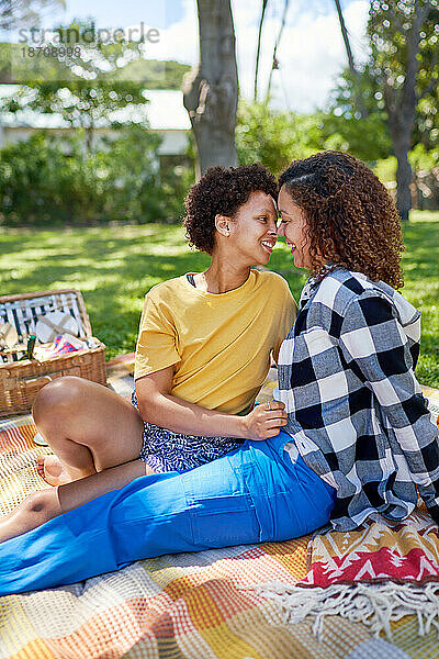 Glückliches  liebevolles lesbisches Paar auf Picknickdecke im Park