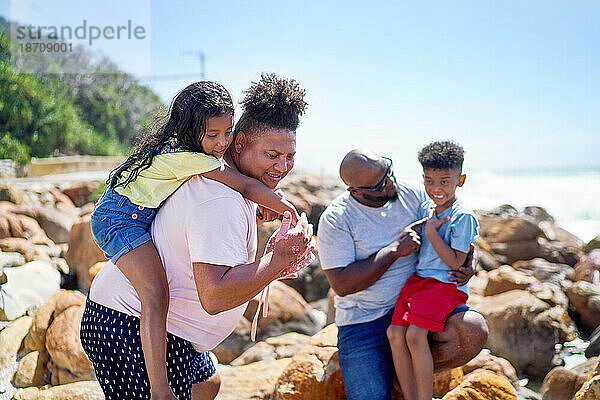 Schwules männliches Paar mit Kindern auf sonnigen Strandfelsen
