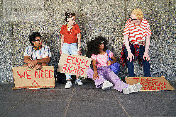 Junge Freunde mit Gleichberechtigungsschildern ruhen an der Wand
