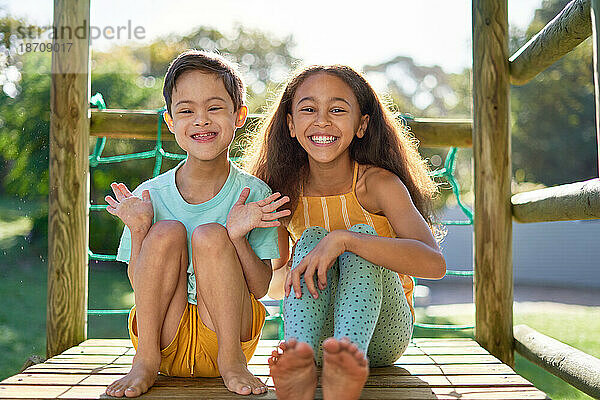 Porträt einer glücklichen Schwester und eines Bruders mit Down-Syndrom auf dem Spielplatz