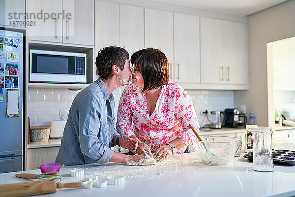 Liebevolles lesbisches Paar backt und küsst sich zu Hause in der Küche