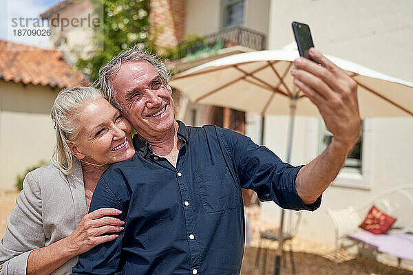 Glückliches älteres Paar macht Selfie vor der sonnigen Villa