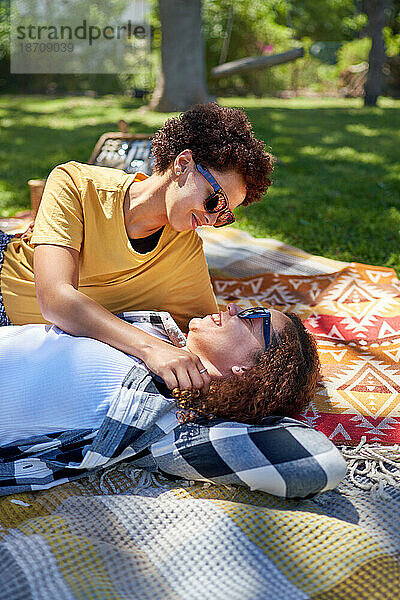 Glückliches lesbisches Paar kuschelt und redet auf der Picknickdecke im Park