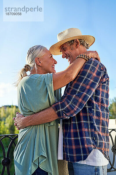 Glückliches  liebevolles älteres Paar  das sich auf dem Balkon umarmt