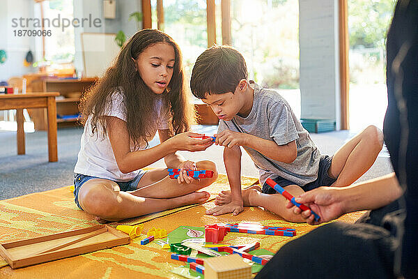 Schwester und Bruder mit Down-Syndrom spielen mit Spielzeug auf dem Boden