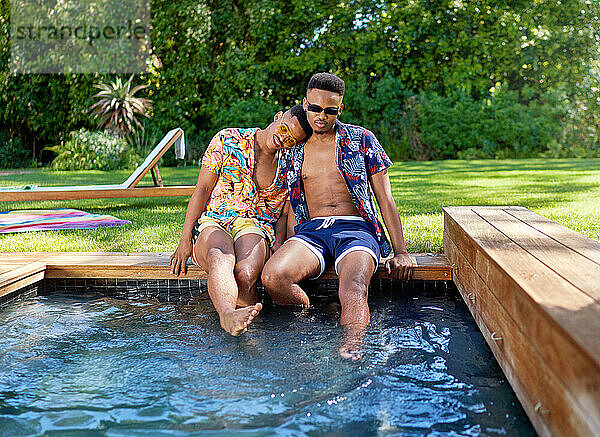Liebevolles junges schwules Männerpaar am Schwimmbad im Hinterhof