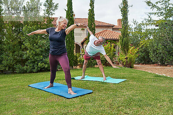 Glückliches  aktives Seniorenpaar  das Yoga im Garten der Villa praktiziert