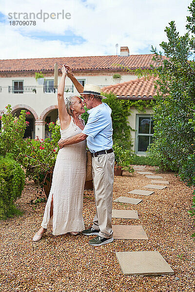 Glückliches älteres Paar tanzt vor der Villa im Sommergarten